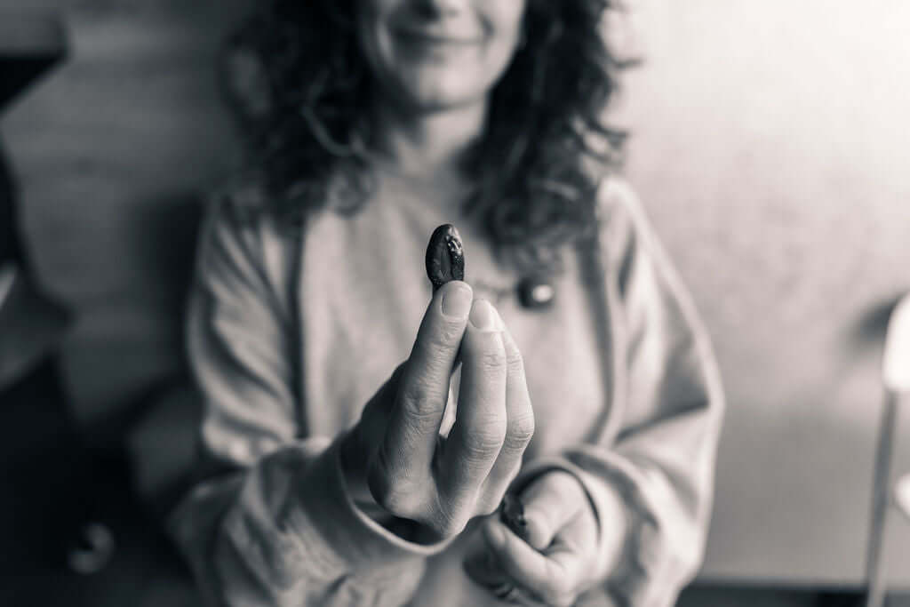 Woman holding a cacao bean, showcasing the source of organic dark chocolate in San Diego.