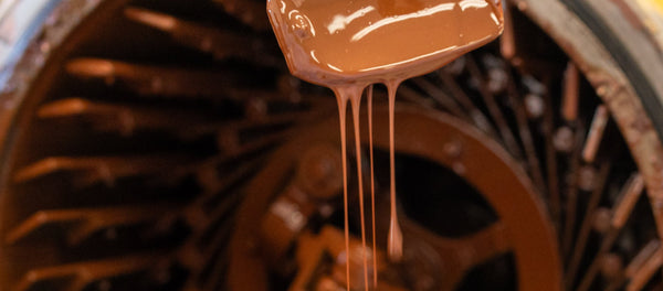 Rich, liquid chocolate dripping from a scoop, showcasing the craftsmanship of San Diego's premium chocolate maker.