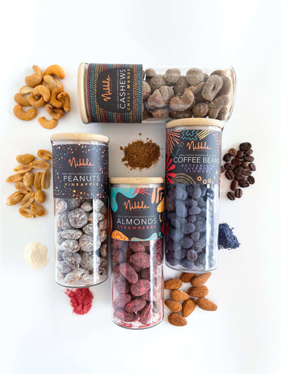 Flat-lay of assorted chocolate-covered nuts and beans glass jars