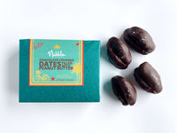 Green Nibble Chocolate box next to chocolate-covered dates on white background