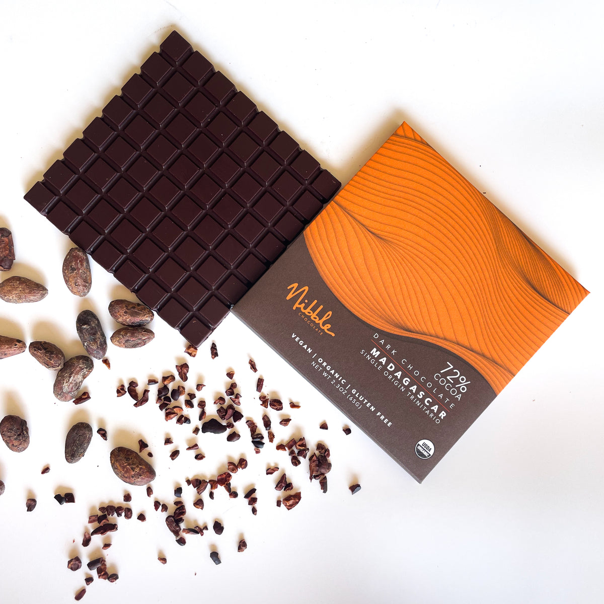 Nibble Chocolate 72% cocoa dark chocolate from Madagascar with cocoa beans and nibs on a white background.