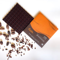 Nibble Chocolate 72% cocoa dark chocolate from Madagascar with cocoa beans and nibs on a white background.