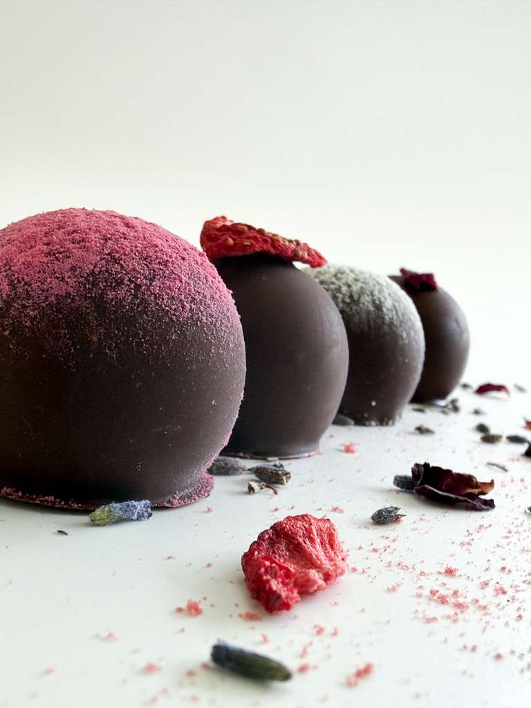 Chocolate truffles with different toppings on a white surface