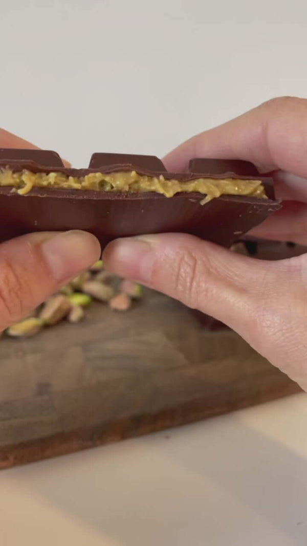 Close-up of hand holding artisan chocolate bar with golden toppings – Dubai chocolate