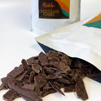 Shaved tempered dark chocolate with open kraft bag and Nibble Chocolate packaging