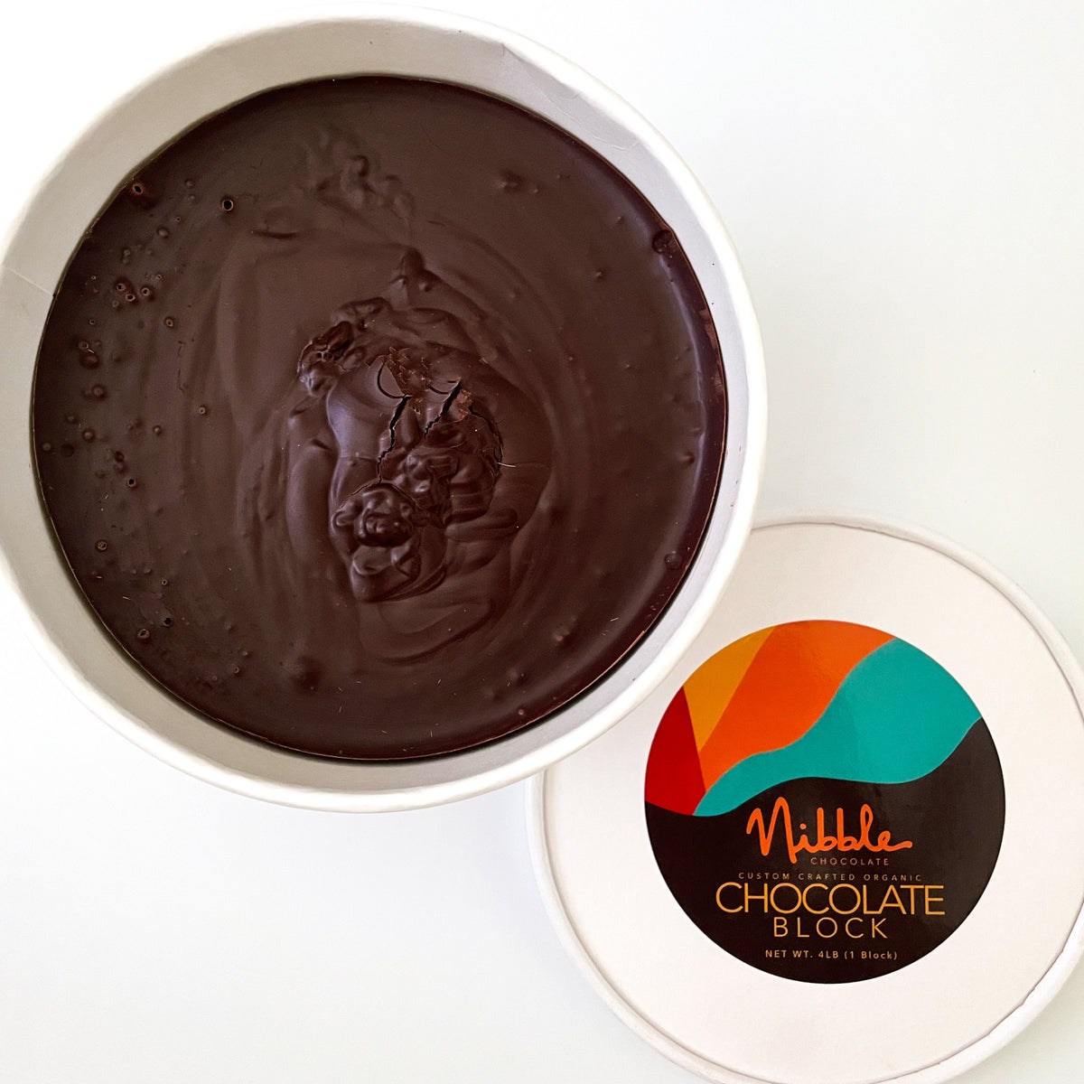 Round tub of tempered chocolate with smooth surface and Nibble Chocolate lid